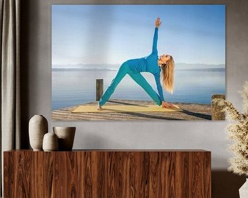 Femme effectuant une pose de yoga en triangle sur un quai sur Markus Gann