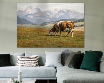 Cow grazing on an alpine meadow with majestic mountain backdrop by Annabell Gsödl