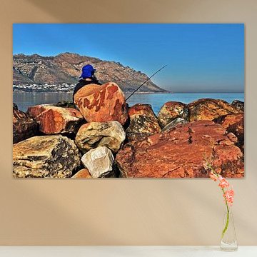un pêcheur sur des rochers rouges au bord de la mer