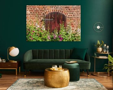 Blühende Stockmalven vor einem Tor 