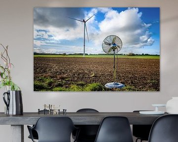 Silver household fan standing on a field in front of a wind turbine by Maren Winter