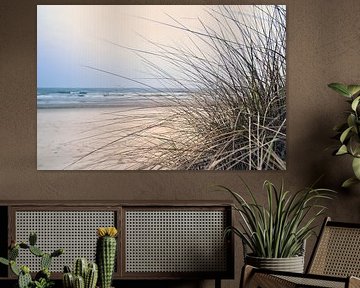 Kustlandschap met duingras op de voorgrond en golven op de achtergrond.