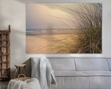 Kustlandschap met duingras op de voorgrond en golven op de achtergrond.