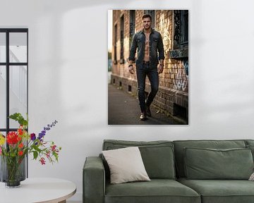 Man in denim shirt en spijkerbroek wandelend langs graffiti muur van Markus Gann