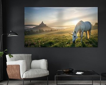 Eenhoorn in weiland met ver kasteel bij zonsopgang van Markus Gann