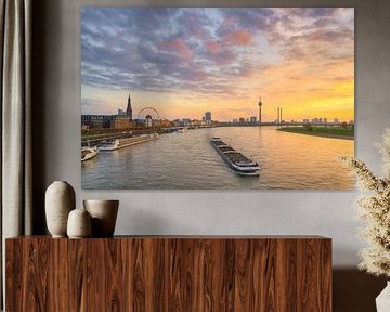 La ligne d'horizon de Düsseldorf avec un bateau sur le Rhin au coucher du soleil sur Michael Valjak