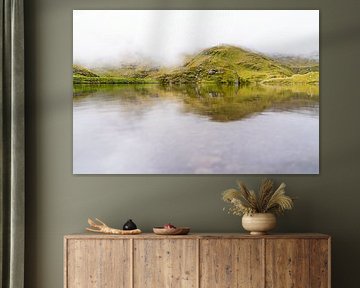 Misty mountain lake in green hilly landscape by Daisy Renders