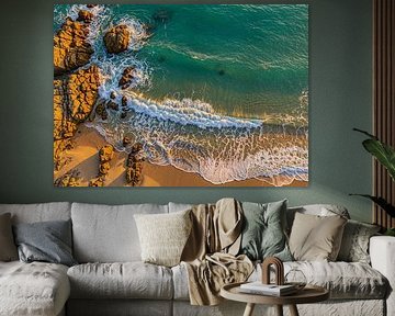 Een top-down drone-perspectief. Het centrale onderwerp blijft de kustlijn waar de oceaan en het zand