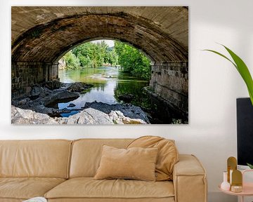 Stenen brug over een rustige rivier omgeven door weelderig groen in spanje van ChrisWillemsen