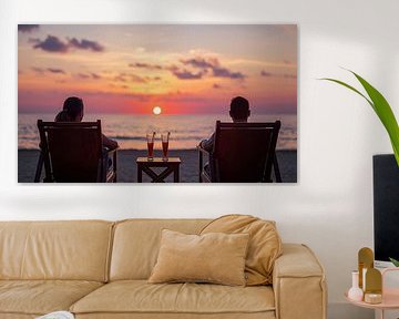 A couple sits on the beach at sunset. by Bo Valentino