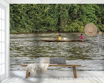 Twee vrouwen en een kind in een kano in Suriname