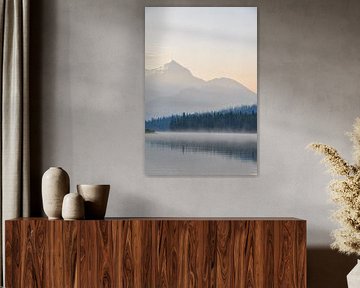 A serene lake in Canada, surrounded by majestic mountains and lush green trees, under a blue sky during sunrise, with dew on the surface of the water. The calm water reflects the landscape, creating a sense of symmetry and balance. The landscape exudes peace and serenity. This is a photo of Maligne lake in Canada. The sunrise gives it beautiful saturated hues. by UMA Digital NL