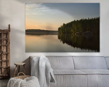 Gouden zonsondergang boven een rustig bosmeer in Scandinavië.