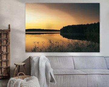 Gouden zonsondergang boven een rustig bosmeer in Scandinavië.