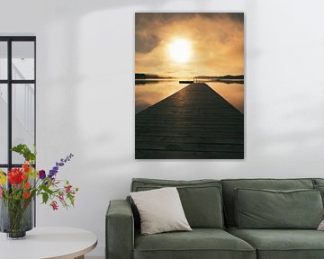 A wooden jetty on the lake in the morning mist, flooded with sunlight and a calm reflection. by Martin Köbsch