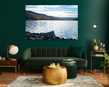 Rustig bergmeer met herfstheuvels en rotsen in het heldere water