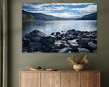 Rustig bergmeer met herfstheuvels en rotsen in het heldere water