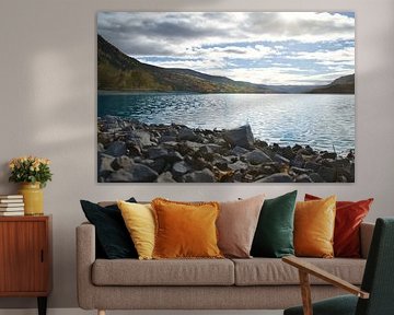 Rustig bergmeer met herfstheuvels en rotsen in het heldere water