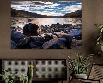 Rustig bergmeer met herfstheuvels en rotsen in het heldere water