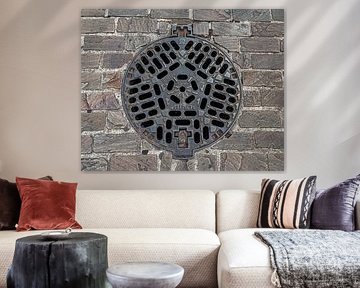 Gusseiserner Kanaldeckel in Pflastersteinen von MMFoto