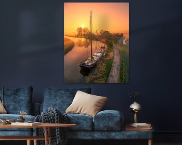 Bateau dans le canal au lever du soleil brumeux sur Ewold Kooistra