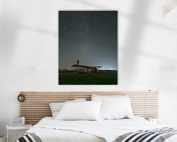 Persoon op verlaten vliegtuig onder sterrenhemel van Ewold Kooistra