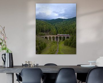 Train sur un viaduc en pierre dans un paysage montagneux verdoyant sur Ewold Kooistra