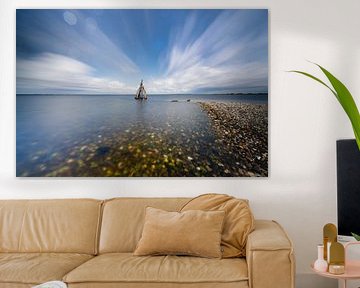 Sculptures on the coast beneath dancing clouds above calm waters