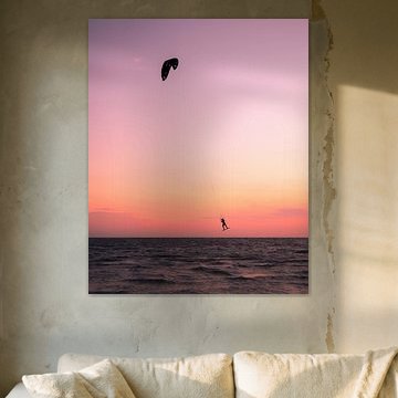 Kitesurfer floats above the sea during a pink sunset by Ewold Kooistra