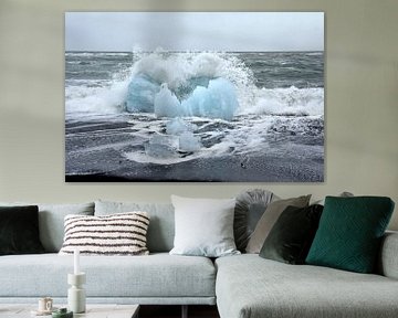 Blue ice floe on volcanic beach near Jokulsarlon. A wave breaks around it. sur Jutta Klassen