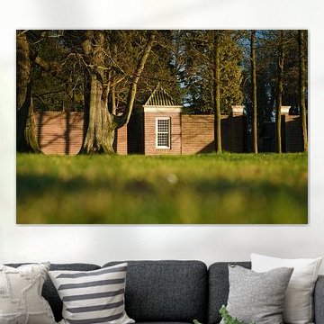 An old brick wall with mature trees bathed in the golden hour light by Fotografiecor .nl