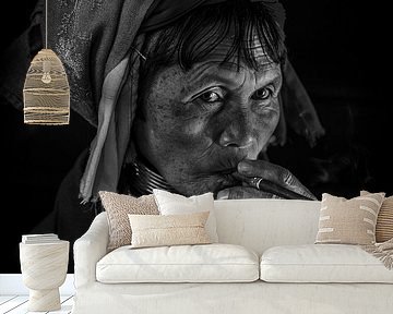 Old woman from the long neck tribe in Inle smoking a cheroot cigar by Wout Kok