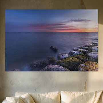 Ein ruhiger Sonnenaufgang über dem Markermeer bei Edam mit moosbewachsenen Steinen und farbenprächtigem Morgenhimmel in Nordholland von Bram Lubbers