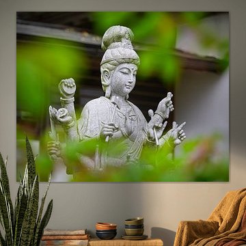 Zen-Guanyin-Statue durch grünes Laub von Gayane Nakada