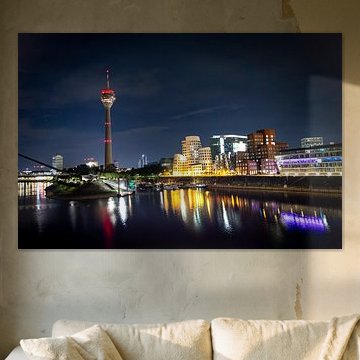 Düsseldorf’s Medienhafen at night, featuring Gehry’s buildings, the Rhine Tower and the illuminated harbour basin / marina