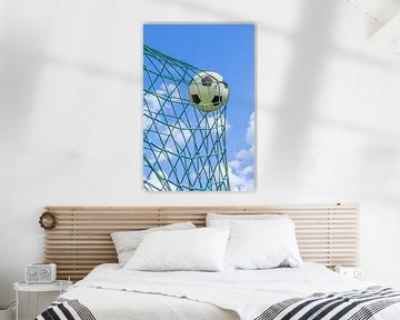 Football caught in goal net with blue sky by Ben Schonewille