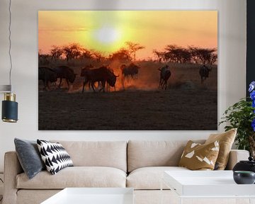 Sunset with wildebeest running away by Annette van den Berg