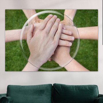 Handen op elkaar in glazen bol boven gras.