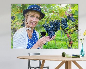 Vrouw in wijngaard toont blauwe druiven met wijn van Ben Schonewille