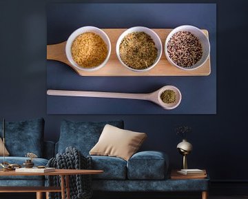 Houten plank met quinoa, rijst en couscous in witte schaaltjes - houten lepel met kruiden sur Malu de Jong