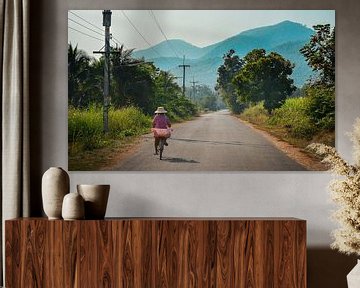 Vrouw fietst over Thaise platteland, Sukhothai van Nick Hartemink