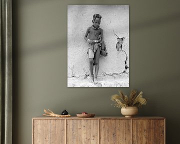 Himba kind tegen de muur van de hut.