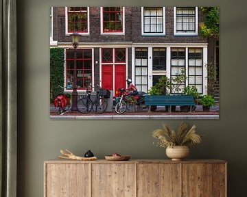 Grachtenpand in Amsterdam met rode deuren en motorrijder in rood von Suzan Baars