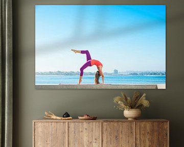 Jonge vrouw beoefent yoga op een smalle muur aan de kust van BeeldigBeeld Food & Lifestyle