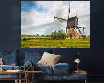 Nederlandse poldermolen contrasterend tegen de bewolkte hemel van Ruud Morijn