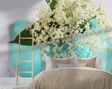 Fresh elder flowers and leaves inside ball of yarn and on pink enamel spoon