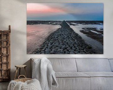 Drooggevallen pier in de Waddenzee bij zonsondergang.