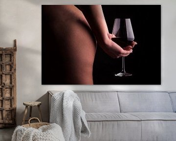 Een foto van een naakte vrouw die een glas wijn vasthoudt achter haar rug.  van Retinas Fotografie