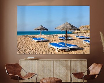 Groep rieten parasols en blauwe ligbedden op strand in Albufeira Portugal