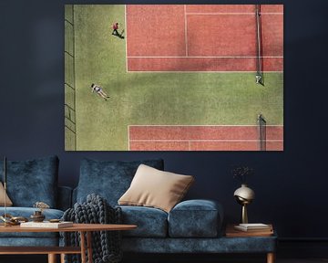 Tennisbaan in vogelvluchtperspectief met een zonnend meisje en een tennisspeler